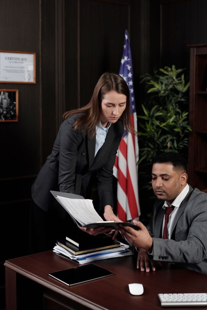 Business professionals discussing documents in a US-themed office setting.