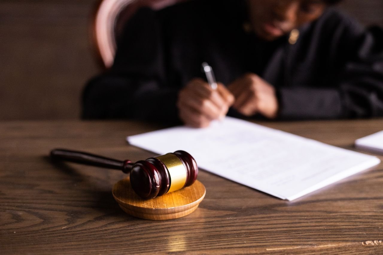 About Judge signing documents at desk with focus on gavel, representing law and justice.